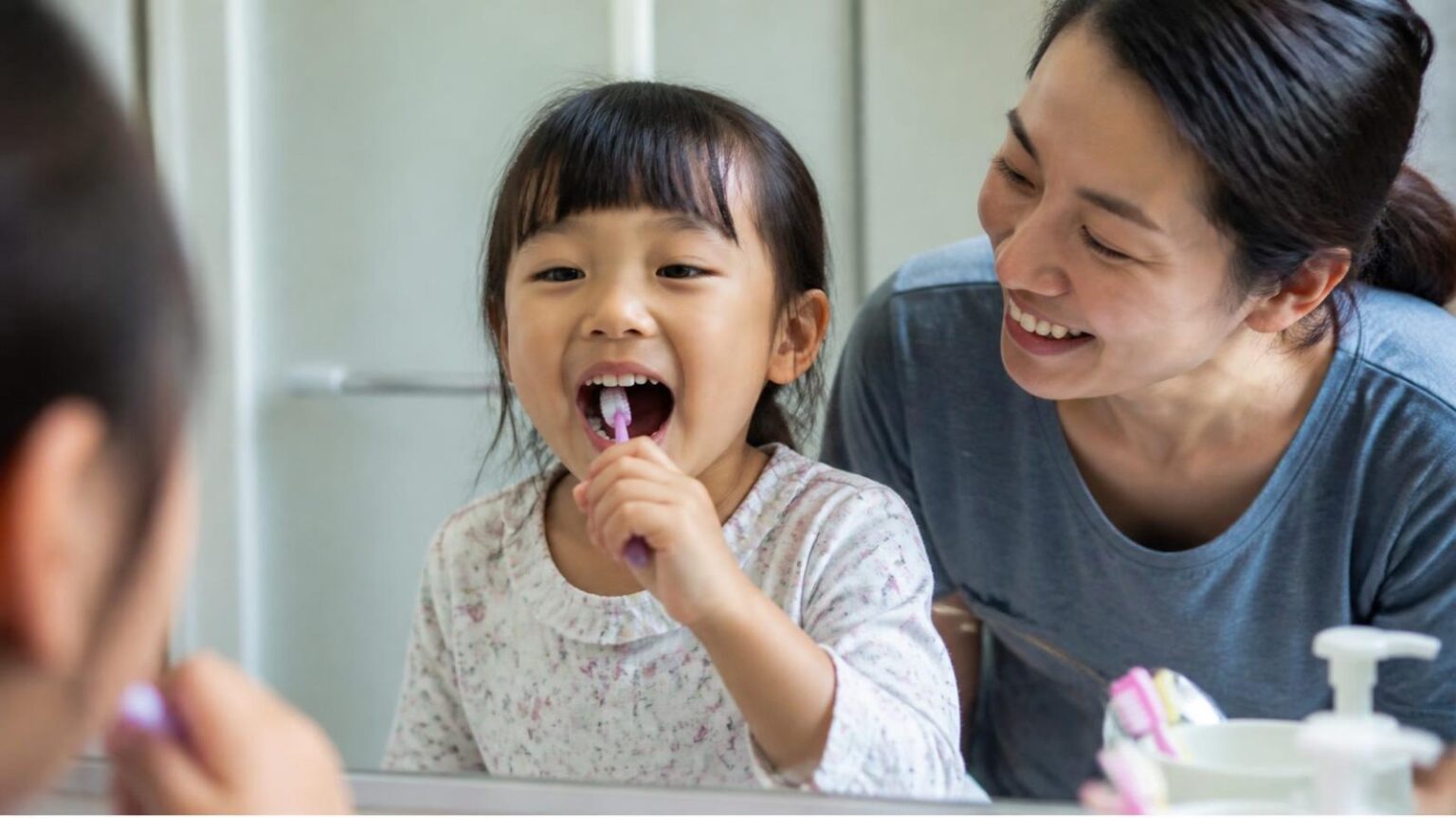 Bé gái đánh răng cùng mẹ trong phòng tắm, chăm sóc răng hàm để dự phòng sâu răng - ảnh minh hoạ Nha khoa Bác sĩ Trung Long Biên