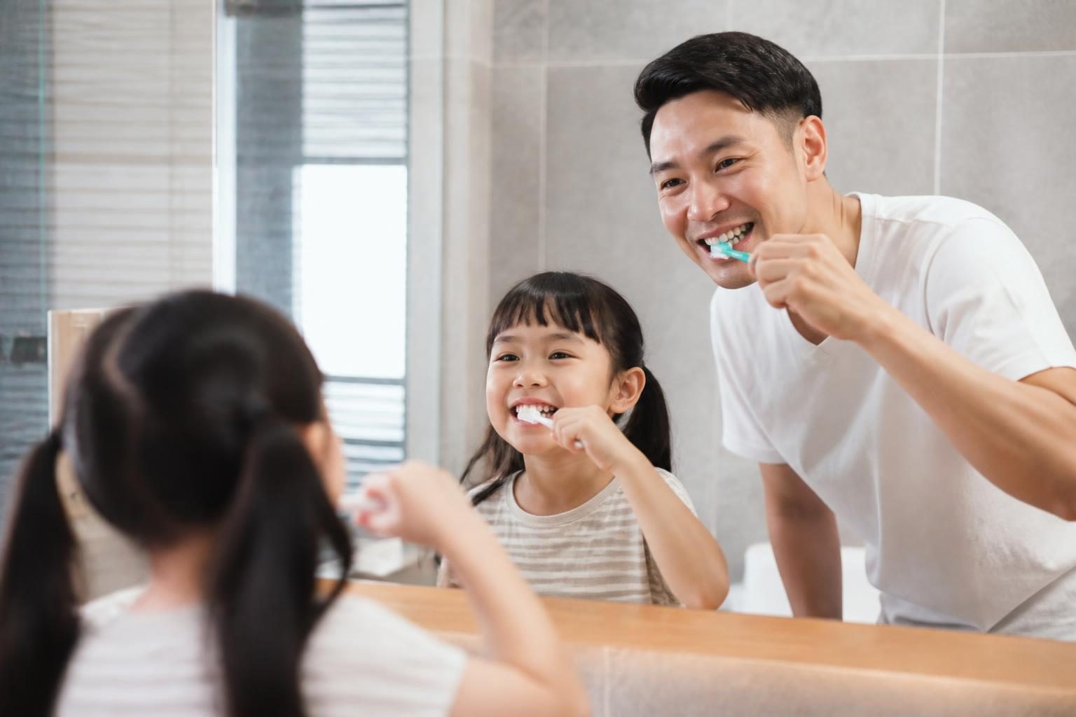 Bố và con gái cùng đánh răng trước gương, vệ sinh răng miệng tốt cho trẻ - ảnh minh hoạ