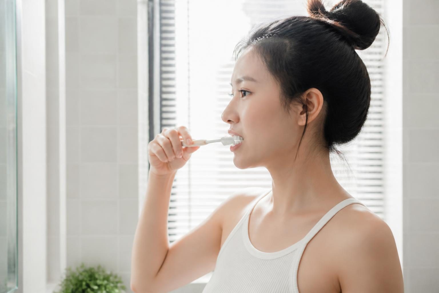 Cô gái đánh răng buổi sáng trong phòng tắm, chăm sóc răng miệng sau niềng răng - ảnh minh hoạ