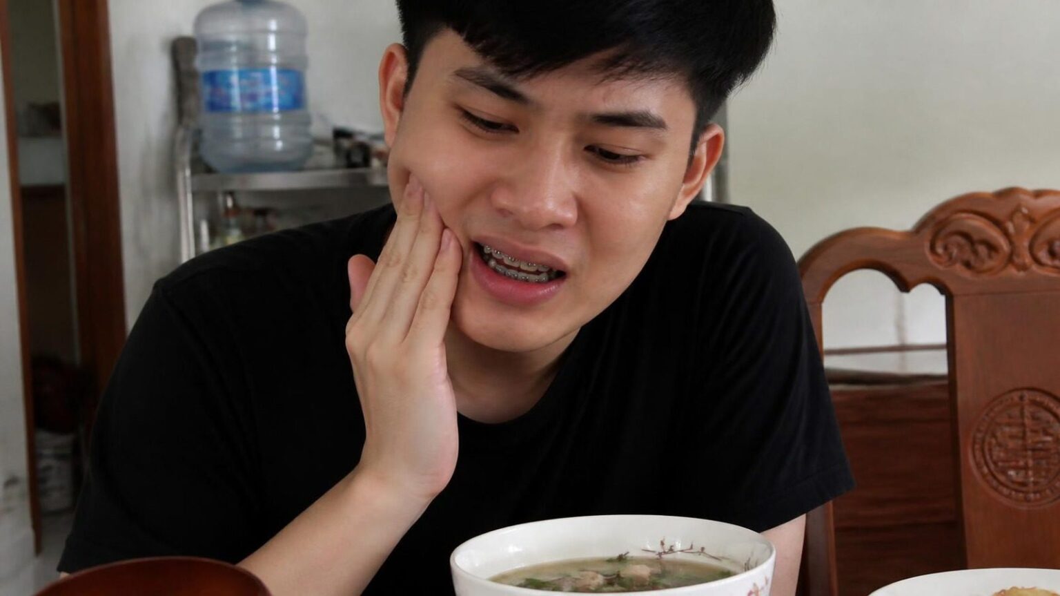Chàng trai đang niềng răng mắc cài chạm má vì hơi ê răng khi ăn - ảnh minh hoạ vấn đề khi niềng răng Nha khoa Bác sĩ Trung Long Biên