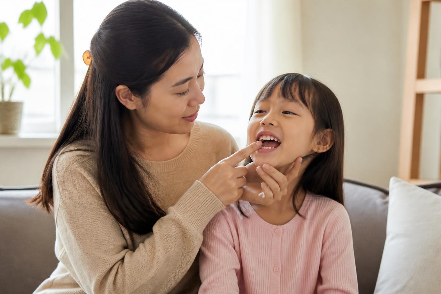 Mẹ ân cần xem răng cửa cho con gái ở nhà, phát hiện sớm đốm trắng trên răng trẻ - ảnh minh hoạ