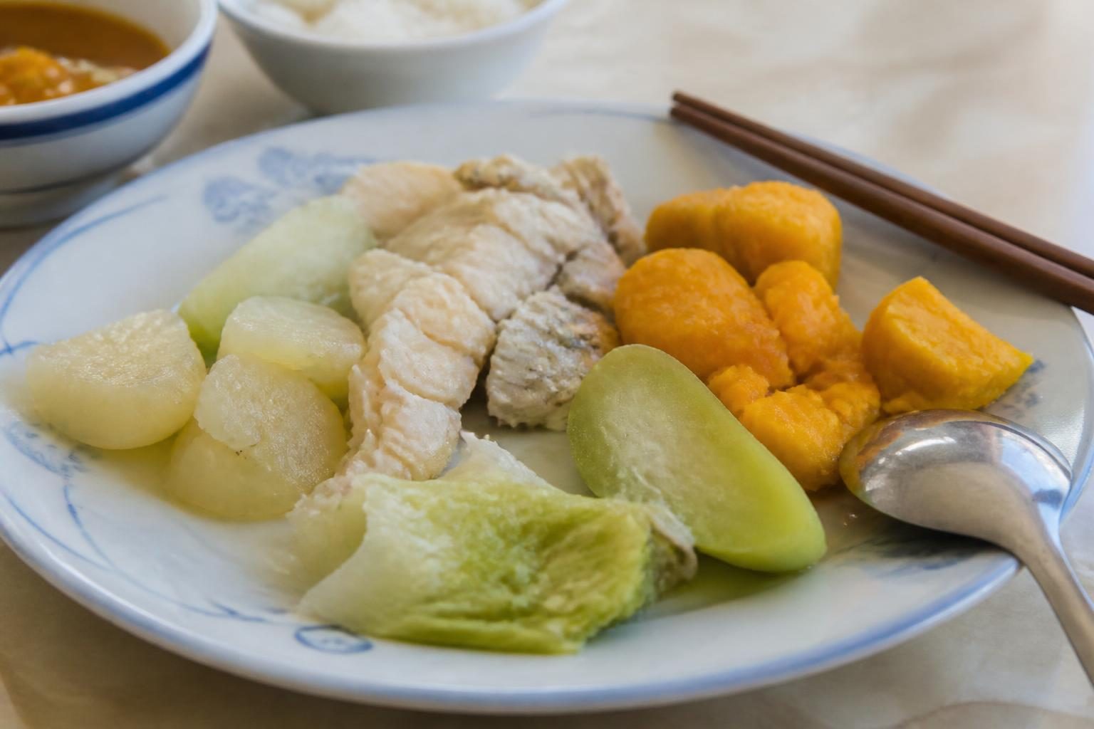 Đĩa cá kho mềm, rau luộc và bí đỏ cắt miếng nhỏ, ăn mềm chứ không phải ăn lỏng khi điều trị khớp thái dương hàm - ảnh minh hoạ