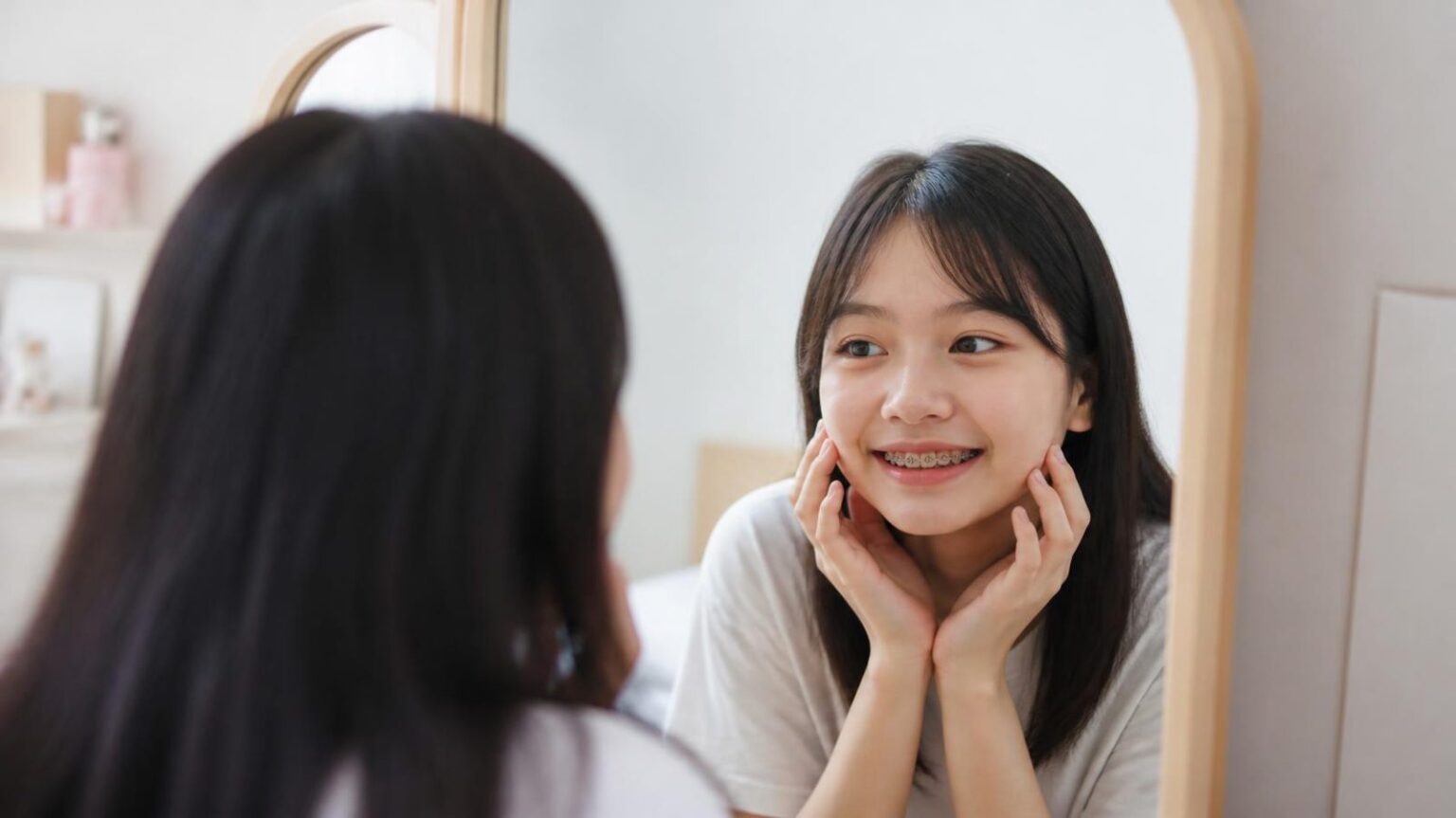 Thiếu nữ đeo mắc cài mỉm cười soi gương, người mới bắt đầu niềng răng - ảnh minh hoạ Nha khoa Bác sĩ Trung Long Biên