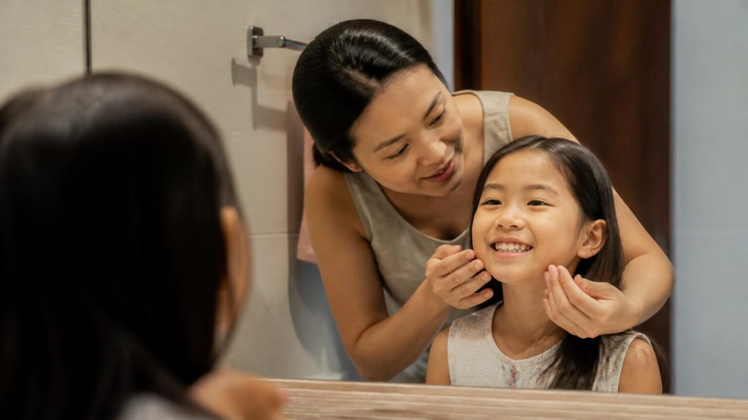 Mẹ cùng con gái soi gương xem răng, quan tâm sai lệch khớp cắn ở trẻ - ảnh minh hoạ Nha khoa Bác sĩ Trung Long Biên