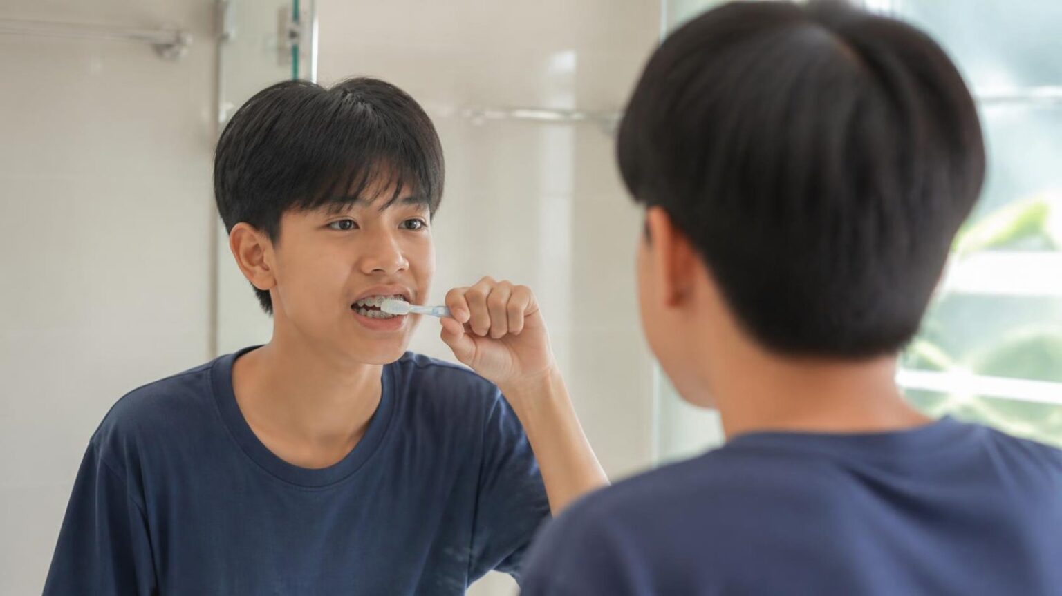 Thiếu niên đeo mắc cài chải răng trước gương ở nhà, vệ sinh răng miệng khi niềng răng - ảnh minh hoạ Nha khoa Bác sĩ Trung Long Biên